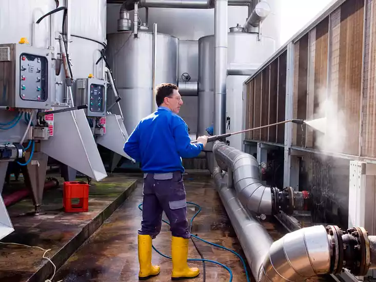 operador limpiando equipo alimentario en planta industrial